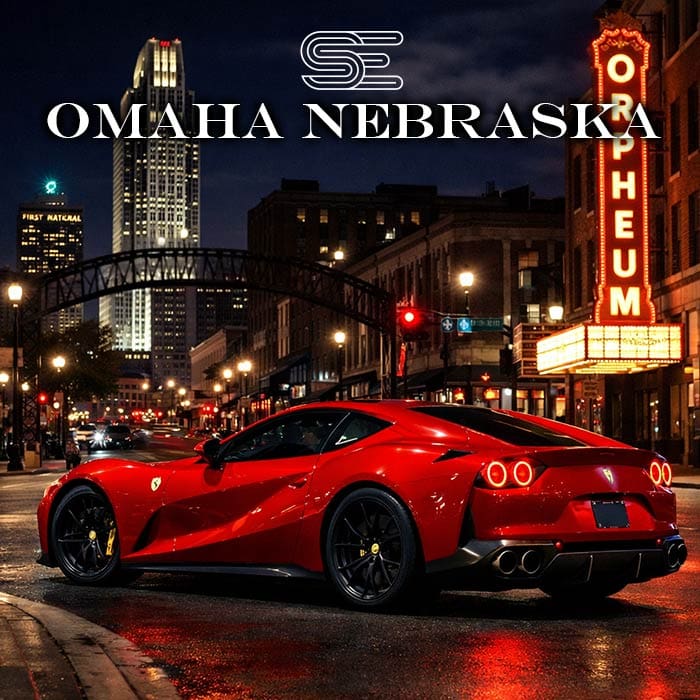Red sports car parked on a city street at night, with Omaha Nebraska and Orpheum Theater signs illuminated in the background.