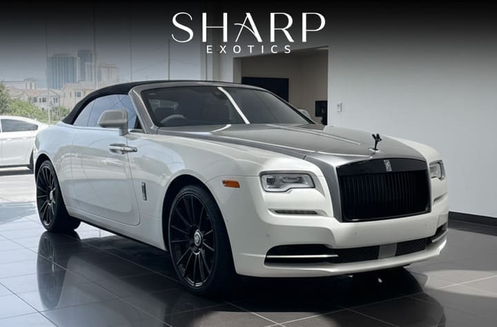 White luxury convertible car with black grille and wheels, displayed indoors under "Sharp Exotics" branding.