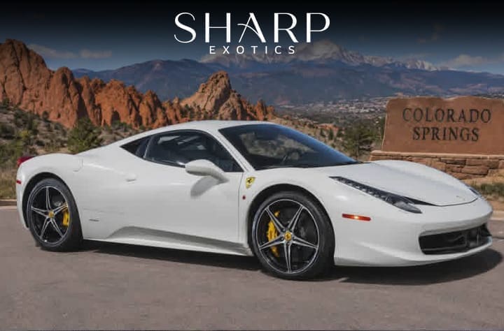 White sports car parked near Colorado Springs sign with red rock formations in the background, under "Sharp Exotics" text.