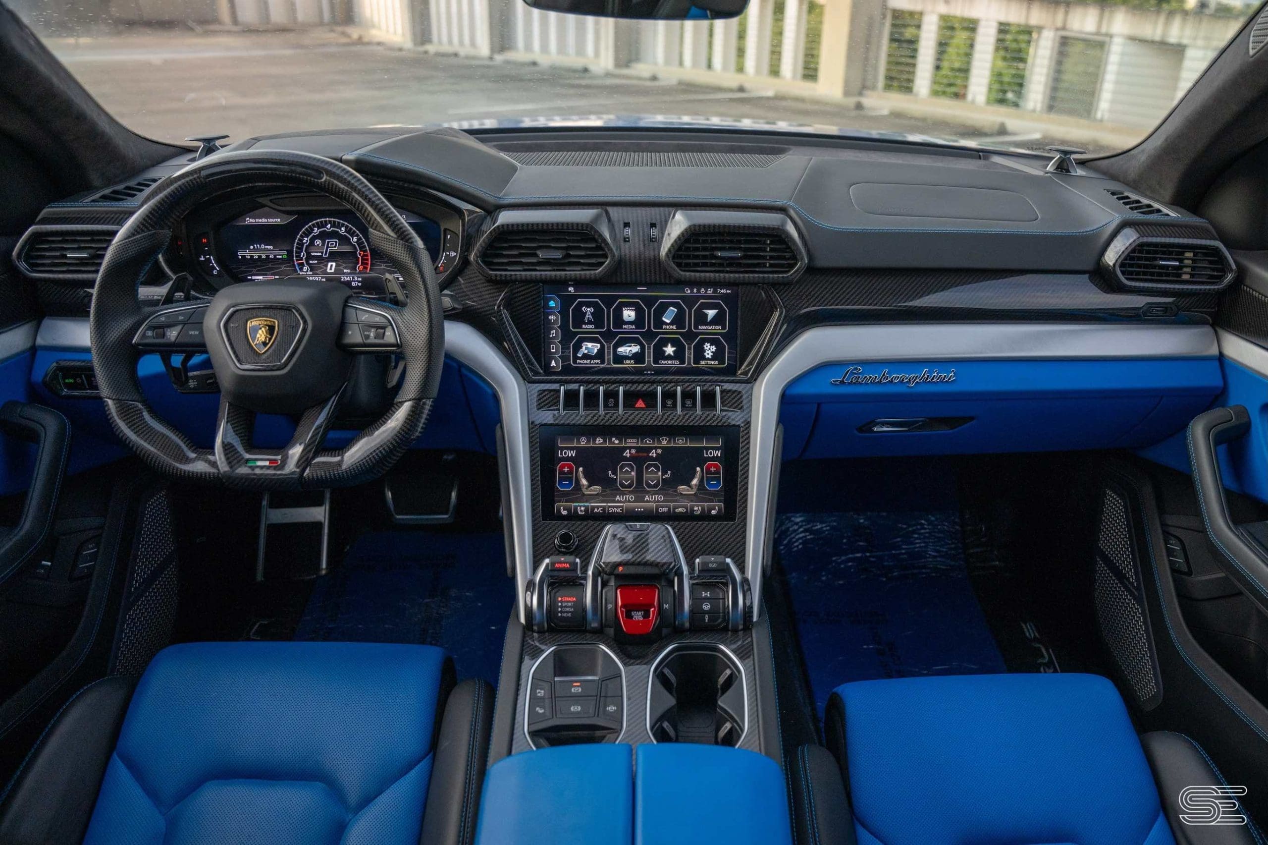 Luxury car interior with a carbon fiber dashboard, digital display, multifunction steering wheel, and blue leather seats.