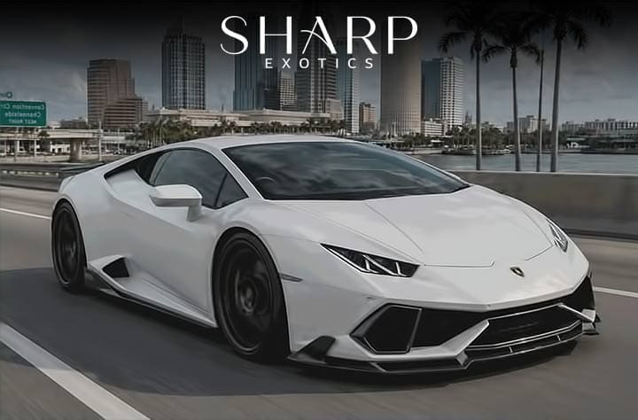 White sports car driving on a city highway with skyscrapers in the background, featuring the text "Sharp Exotics" above.