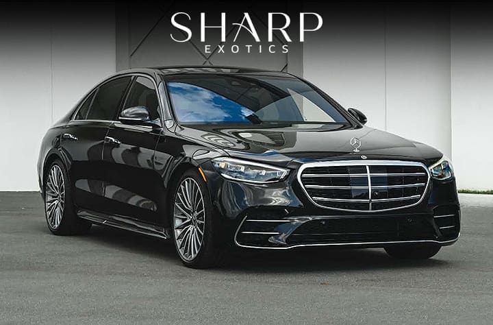 Black luxury sedan parked on a gray surface, featuring a prominent front grille and sleek design, with "Sharp Exotics" text above.